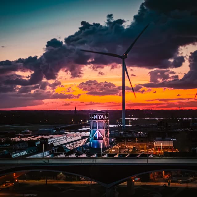 De NYMA watertoren bij zonsondergang, met een windmolen tegen een oranje lucht