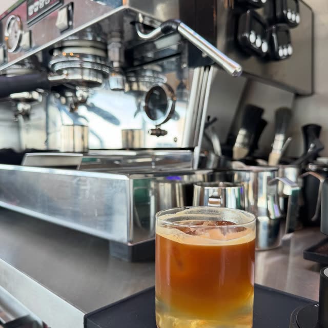 Een amberkleurig drankje op de bar, naast de espressomachine