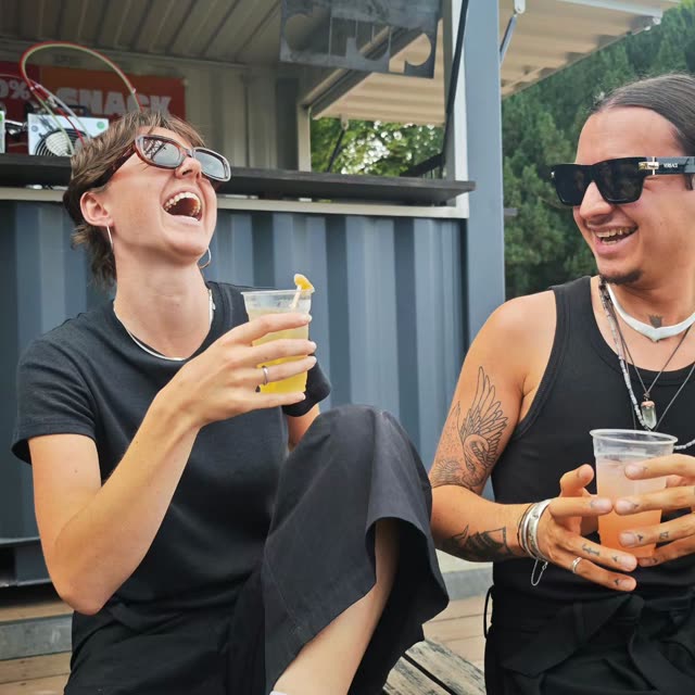 Twee lachende mensen met een drankje in de zon