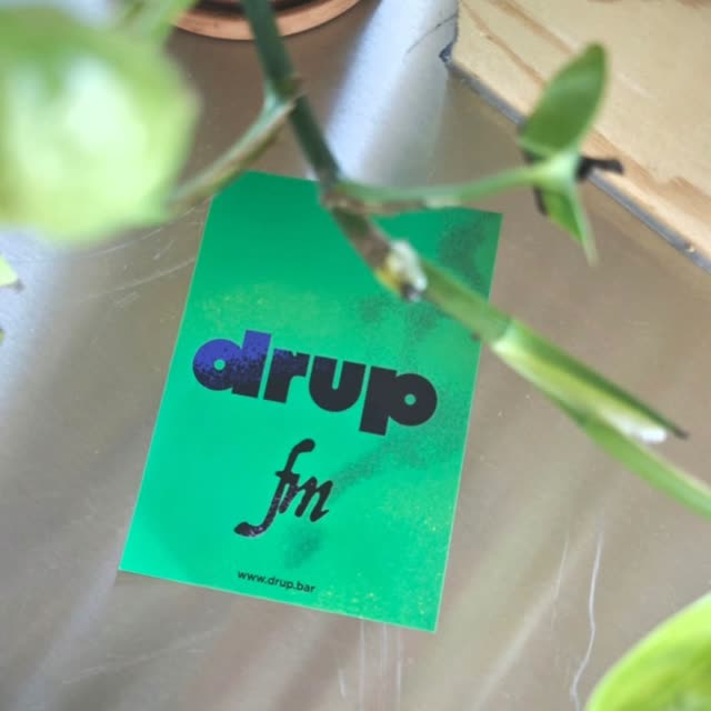 Een groene drup.fm-flyer tussen de planten